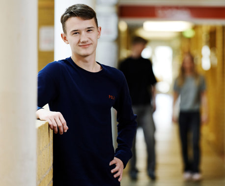 Smilende dreng og to elever i baggrunden