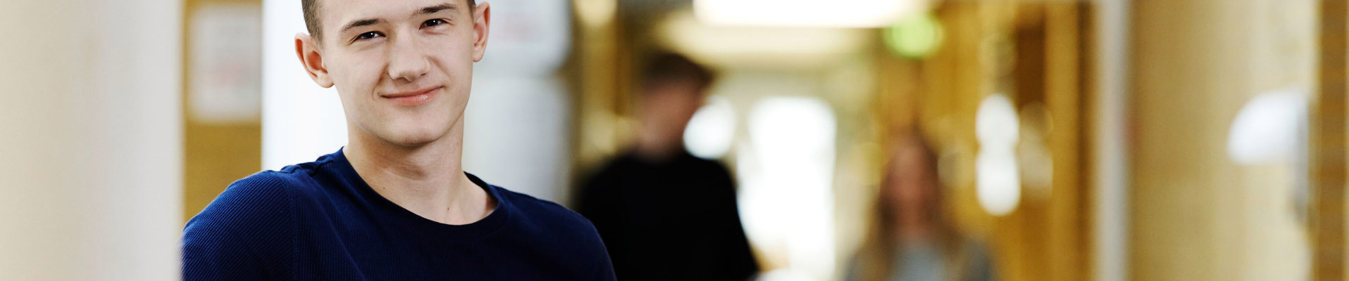 Smilende dreng og to elever i baggrunden