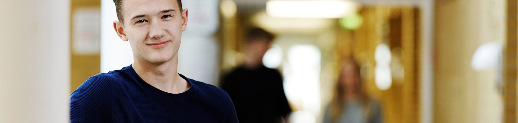 Smilende dreng og to elever i baggrunden