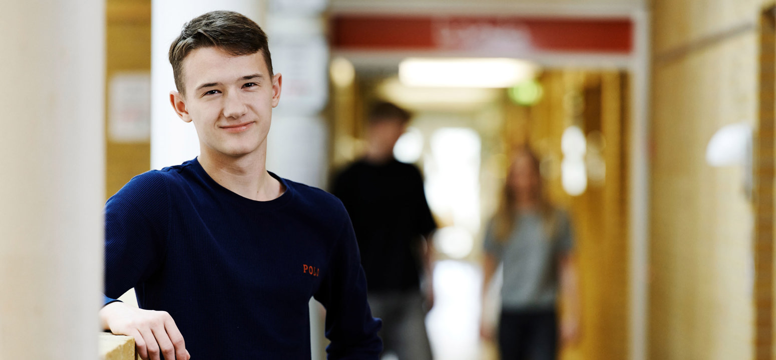 Smilende dreng og to elever i baggrunden